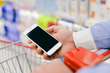 Man holding smart phone and reading text message during shopping