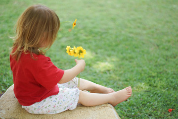 Little girl playing with flowers in garden
