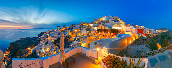 Panoramic famous view, Old Town of Oia or Ia on the island Santorini, white houses and windmills at sunset, Greece - obrazy, fototapety, plakaty