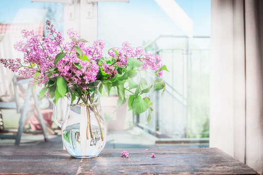 Home interior with Bouquet  of blooming lilac flowers on the table in front of window