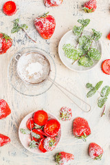 Fresh ripe strawberries with mint leaves and icing sugar on white wooden background, top view