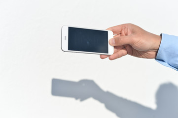 Hand holding mobile phone on white background. Photo closeup 