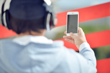 Man with headphones holding mobile smart phone on outdoors background