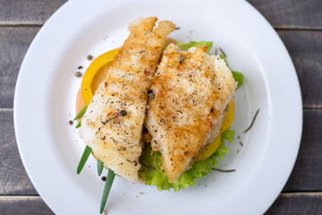 Grilled fish on the toast with pepper and green onion on the plate