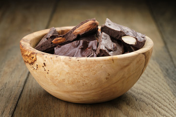 homemade chocolate with almonds in wood bowl, on wood table
