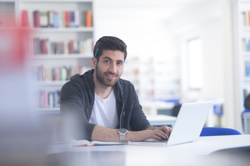 student in school library using laptop for research