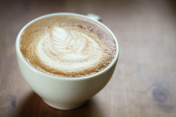 fresh hot cup of coffe with latte art on wood table, shallow focus