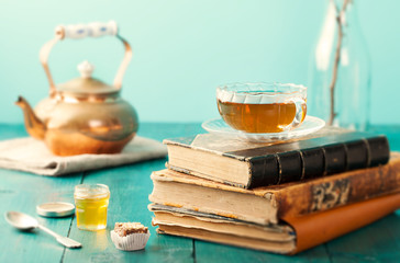 Cup of tea with teapot and vintage books on wooden table