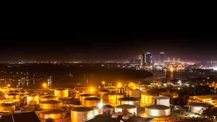 Fototapeta premium Industrial oil tanks in a refinery with building cityscape backg
