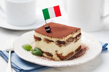Tiramisu, traditional Italian dessert on a white plate with Italian flag.