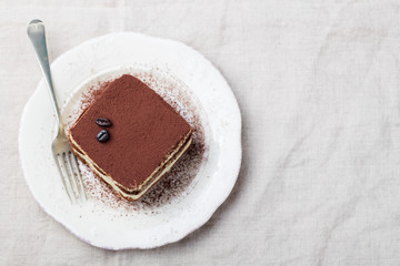 Tiramisu, traditional Italian dessert on a white plate Top view