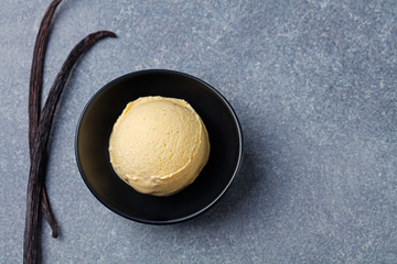 Homemade vanilla, caramel ice cream in black bowl with vanilla pods. Organic product Top view Copy space