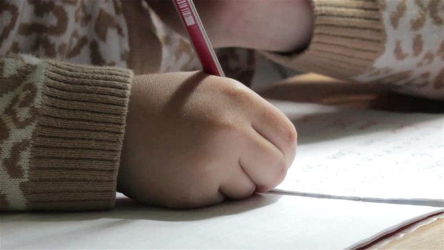 schoolchild writes a pencil a exercise  book/pen writing in a notebook on a desk School