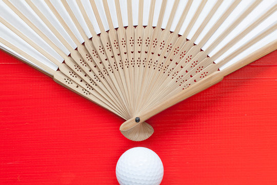 Japanese Hand Fan Made And Golf Balls On The Red Table