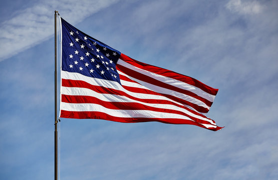 Flag USA waving in wind blue sky and clouds
