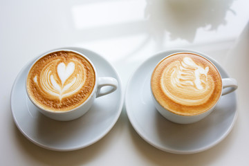 white two cups of Cappuccino coffee with froth heart and bird sh