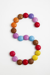 La lettera S formata da coloratissimi confetti di cioccolato.
