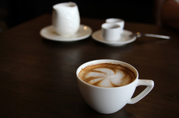 Cup of cappuccino art coffee with froth shape plumeria and woode