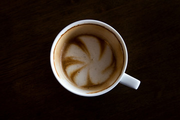Cup of cappuccino art coffee with froth shape plumeria and woode