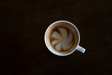 Cup of cappuccino art coffee with froth shape plumeria and woode