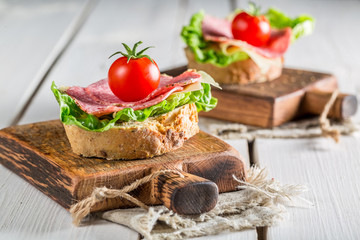 Tasty sandwich with salami, tomato and lettuce