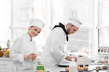 Male and female chefs working at kitchen