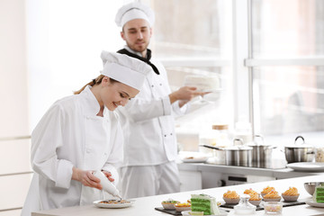 Female chef decorating cookies with chocolate.