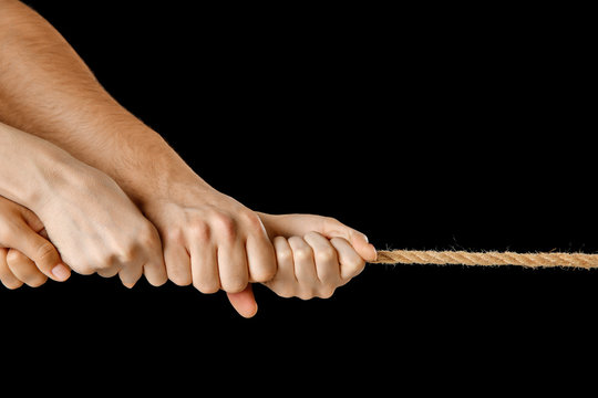 People hands pulling the rope on black background