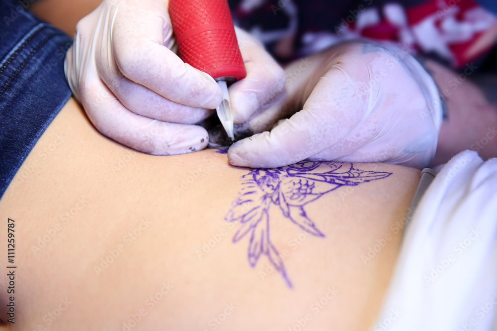 Wall mural Master doing tattoo on female  body, closeup