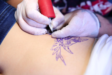 Master doing tattoo on female  body, closeup