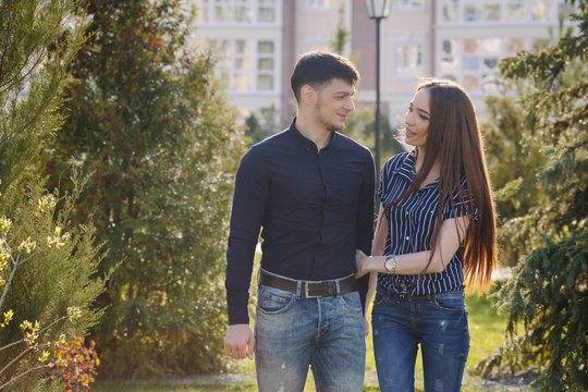 Young couple walking in park smiling back light