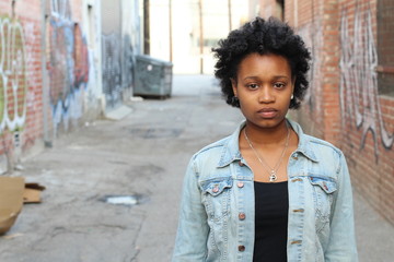 Close up of worried Black woman on isolated dirty alley with graffities background