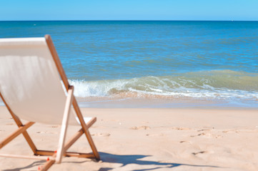 Back view of deckchair on a beach, sunny blue ocean sky outdoors background 