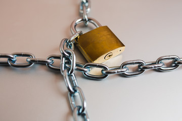 Heavy with a padlock around a laptop isolated on grey table.