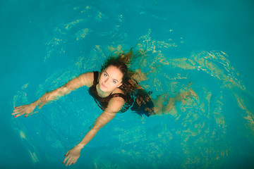 Woman floating relaxing in swimming pool water.