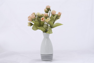 Artificial roses in a vase on a white background.