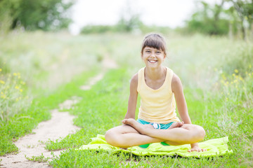 Naklejka na ściany i meble Happy young girl practicing yoga outdoors
