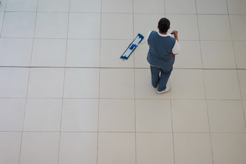 Woman cleaning floor at department store. View from above. Selec