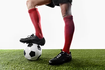 Zelfklevend Fotobehang legs feet of football player in red socks and black shoes posing with the ball playing on green grass pitch © Wordley Calvo Stock