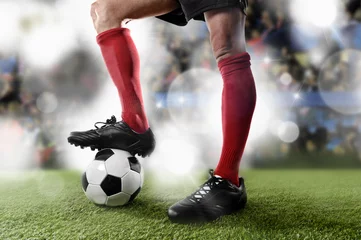 Fototapeten football player in red socks and black shoes plaing with the ball standing on stadium pitch © Wordley Calvo Stock