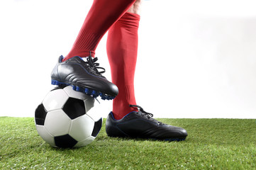 Obraz premium legs feet football player in red socks and black shoes posing with the ball playing on green grass pitch