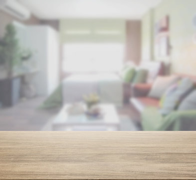 wooden table top with blur of colorful  bedroom interior as background
