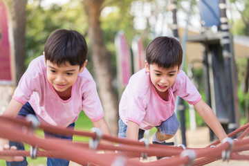 Two Little asian boy climbing rope obstacle activity on the play