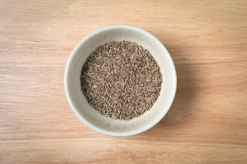 bowl of dried cumin seed on the wood background