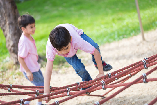 Two Little asian boy climbing rope obstacle activity on the play