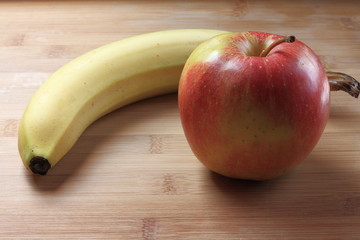 Naklejka premium Apple and banana on a wooden table