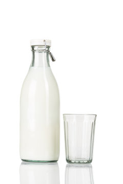 Empty faceted glass stands near a traditional closed old fashioned bottle of milk on white isolated background.