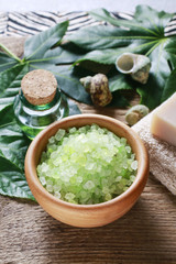 Bowl of green sea salt, bottle of essential oil and bars of soap