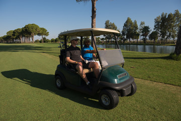 golf players driving cart at course