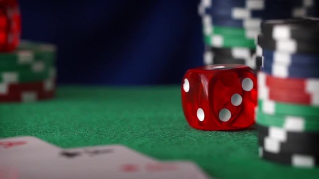 Red dice rolls, casino chips, cards on green felt